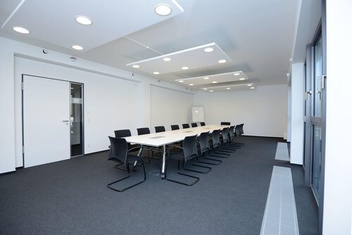 Ein großer, moderner Konferenzraum mit einem langen weißen Tisch und vielen schwarzen Stühlen. Er steht symbolisch für die wichtigen Entscheidungen, die bei der Pensionskasse der Hamburger Hochbahn Aktiengesellschaft -VVaG- getroffen werden.