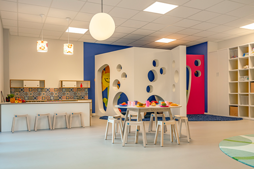 Blick in einen Gruppenraum in einer Kita mit Spielküche und einem großen Spielhaus. Ein Bild für die Förderung von Familien durch die Pensionskasse der Hamburger Hochbahn Aktiengesellschaft -VVaG-.